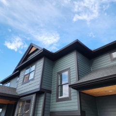 A stylish black house featuring black seamless gutters installed by Call The Gutter Guys, providing a sleek and modern look with optimal water drainage