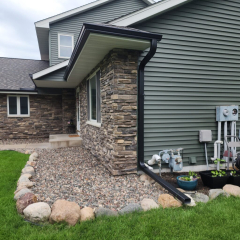 A sage-colored house in Plymouth, MN, featuring newly installed black seamless gutters by Call The Gutter Guys, enhancing the home's exterior contrast and functionality