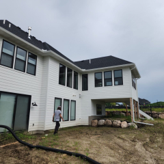 A beautiful white walk-out style home featuring newly installed seamless gutters and a leaf filter system for optimal drainage and protection