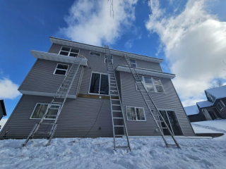 A cozy home surrounded by snow, showcasing a peaceful winter scene with a crisp white landscape getting new gutters