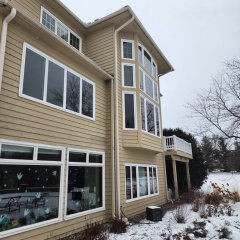Rear view of large 3 story home on a snowy day showing seamless gutters installed by Call The Gutter Guys