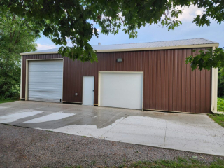 Front view of pole barn with cream colored seamless gutters installed by call the gutter guys to divert water