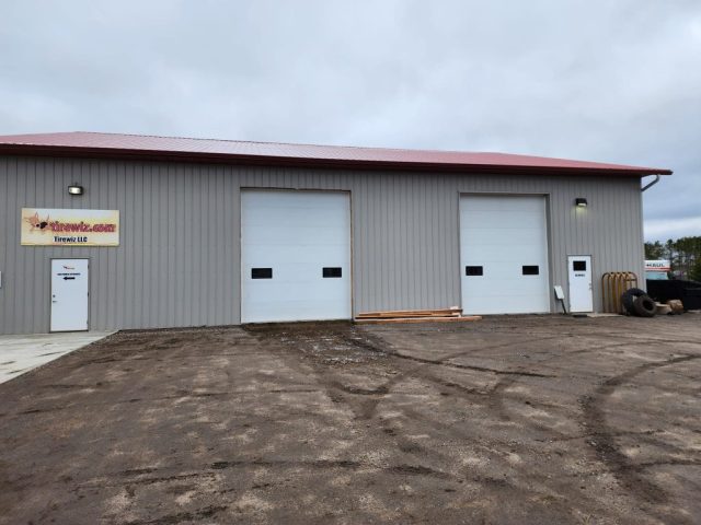 Redwood colored seamless gutters on pole barn in Buffalo and Tirewiz tire and wheel shop by Call The Gutter Guys