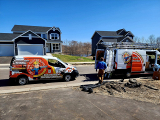 Two Gutter Guy work trucks on-site installing seamless gutters on a residential building