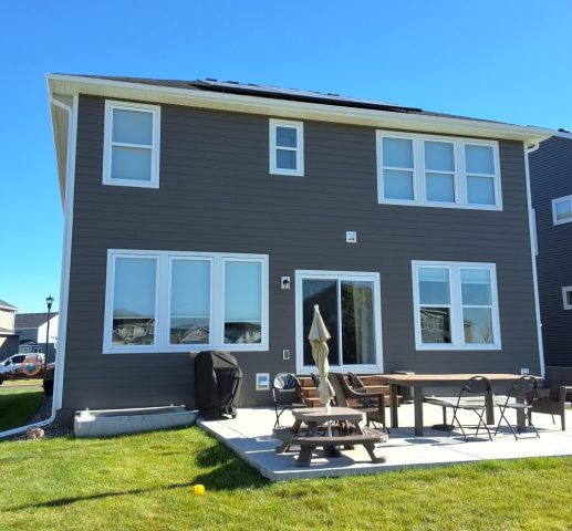 Hip roof home with white seamless gutters showing contrast from gray siding by Call The Gutter Guys