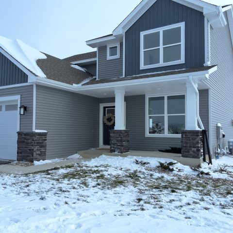 Seamless gutters on front porch overhang on a home in Rogers MN with white downspouts on pillar