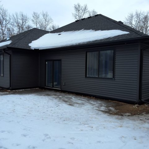 Black seamless gutters installed on a black new construction home in Breezy Point MN