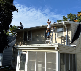 Gerrod and Kevin from Call The Gutter Guys waving from roof as they install new seamless gutters