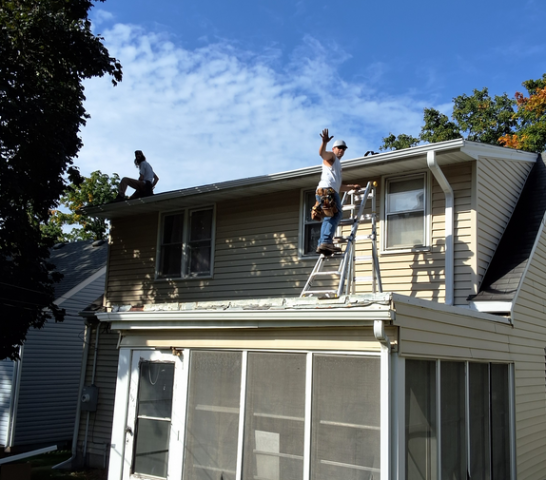 Gerrod and Kevin from Call The Gutter Guys waving from roof as they install new seamless gutters