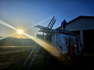 Call The Gutter guys working late installing gutters on a pole barn as the sun sets in Greenfield Minnesota